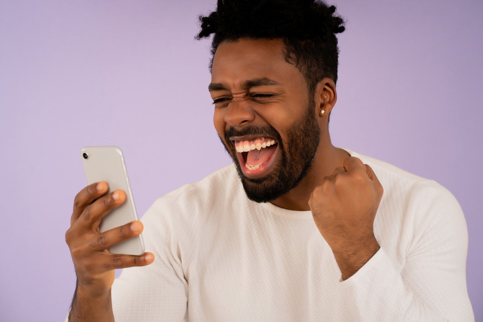 Afro Man Celebrating Victory While Looking at His Mobile Phone.